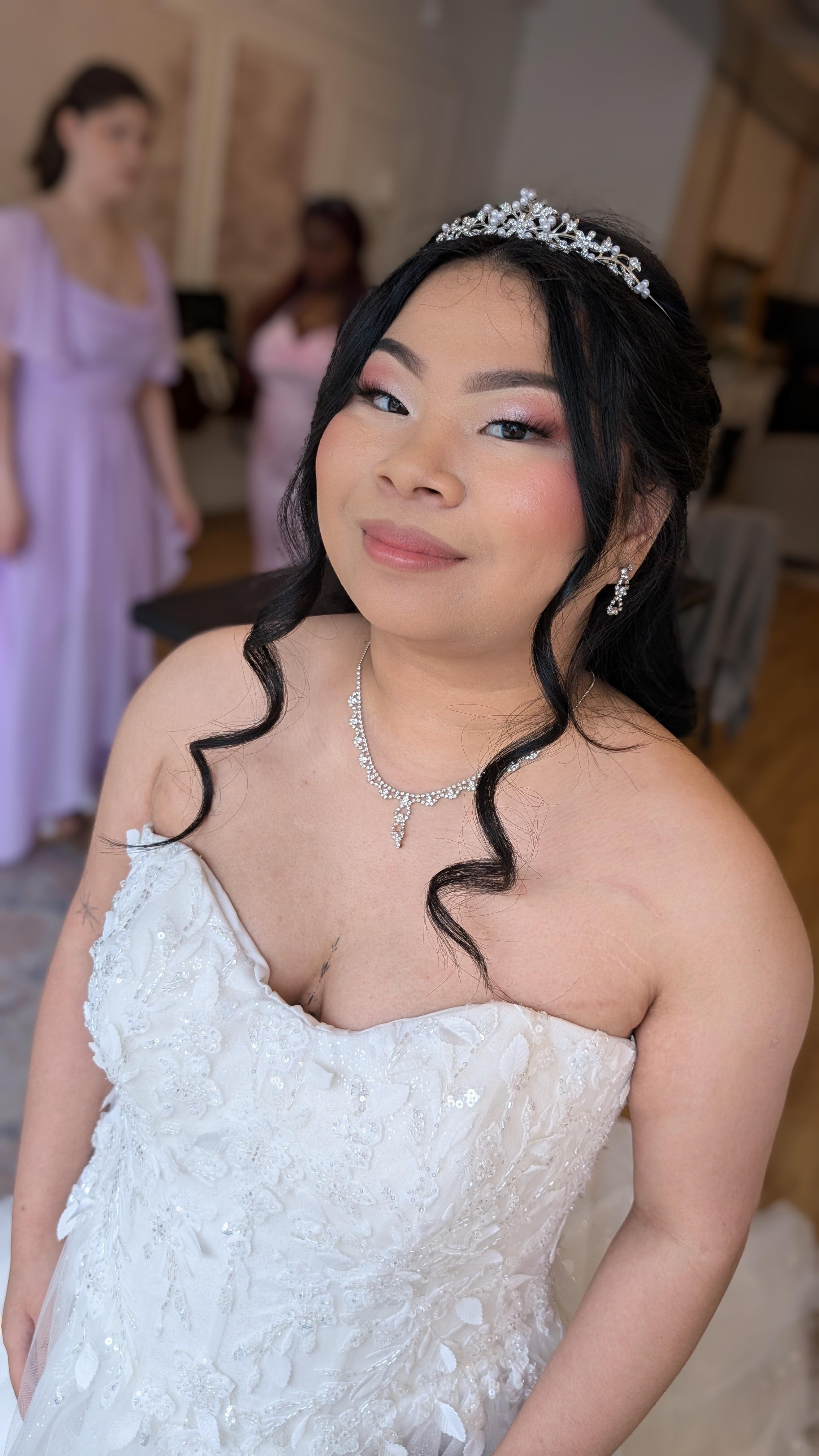 bride wearing a crystal tiara, soft glam makeup and loose curls, in her strapless lace gown
